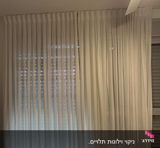וילון לבן שקוף תלוי על חלון עם אור מאחוריו